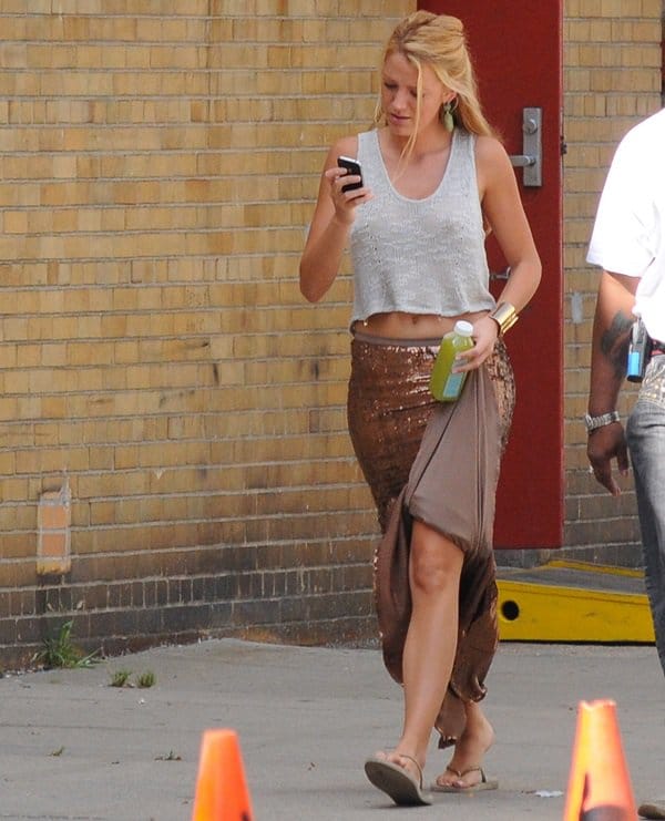 Blake Lively pairs a shimmering Haute Hippie Sequined Mermaid maxi skirt with Havaianas flip flops, a breezy cropped knit tank, gold bangles, and statement earrings while on the Gossip Girl set
