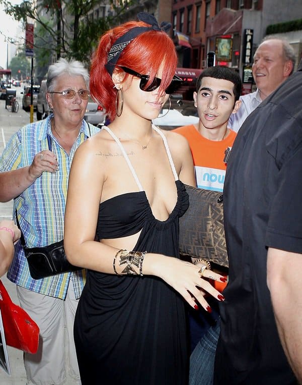 Showcasing her fashion-forward style, Rihanna pairs her breathtaking Torn by Ronny Kobo Sharon maxi dress with a chic Fendi Mia messenger bag and a Prada Logo denim top handle bag