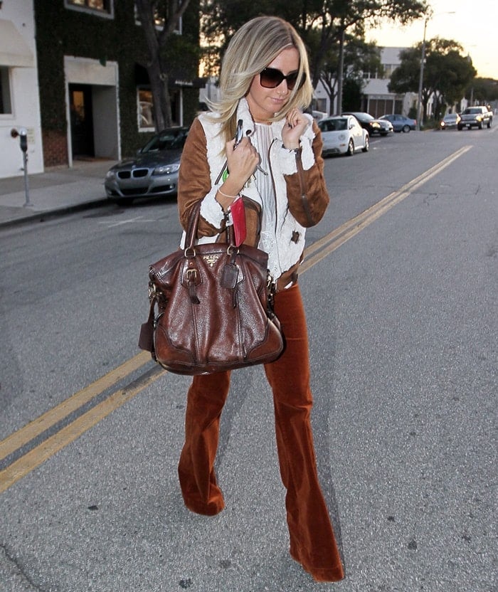 Ashley Tisdale styled a warm-looking faux shearling aviator jacket with corduroy high waist flare pants