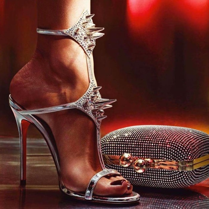 The striking Christian Louboutin 'Lady Max' Spike Sandals, paired with a glimmering studded clutch, make for a bold and glamorous statement perfect for a night out