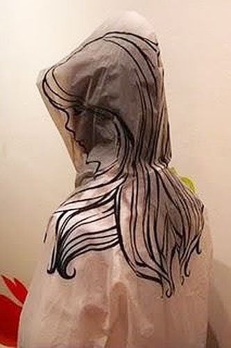 Girl drawing on the hood of a clear raincoat