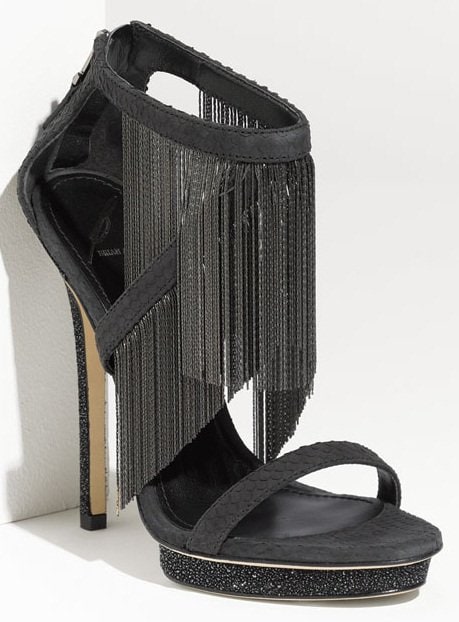 Captivating chain fringe drapes dynamic allure over a strappy, snake-stamped sandal supported by a sparkling platform and heel