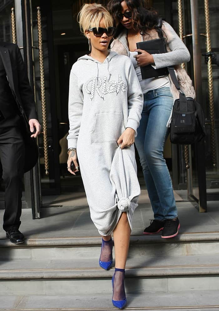 Spotted at the Corinthian Hotel, Rihanna showcases her unique fashion sense with a knotted sweatshirt dress and blue pointy pumps, effortlessly blending comfort with high fashion