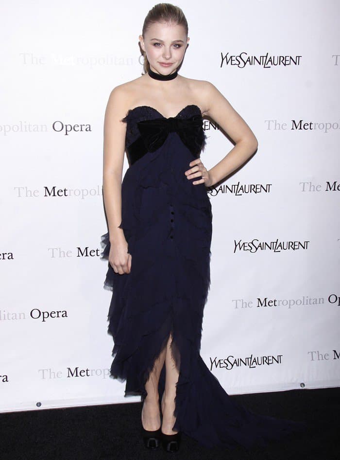 Chloe Moretz styled her choker with a sophisticated navy-and-black dress characterized by cascading ruffles, a velvet-bow bustier, and an elegant train