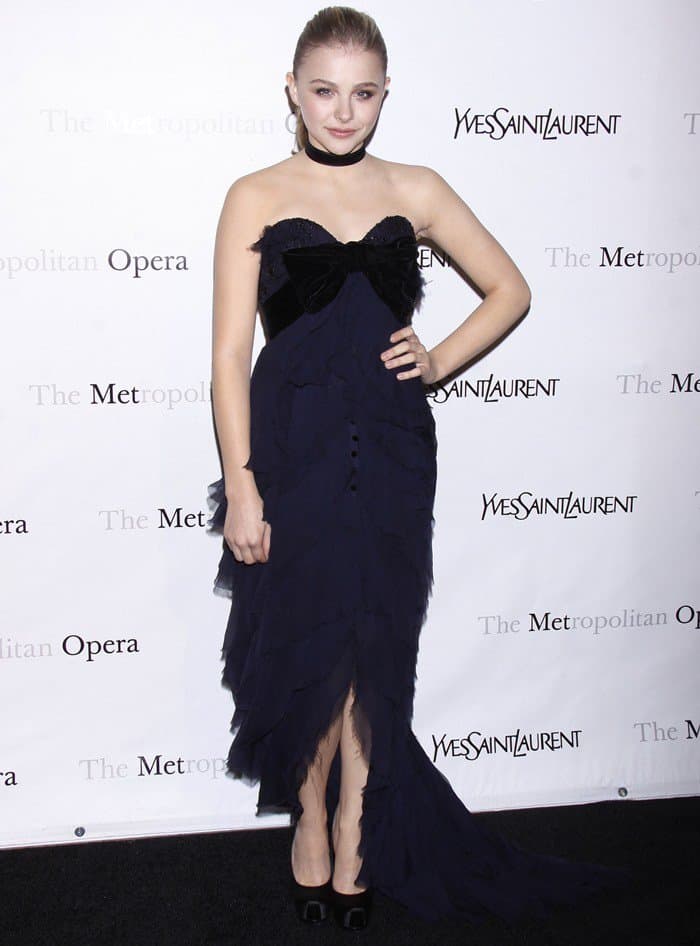 Chloë Grace Moretz styled her choker with a sophisticated navy-and-black dress characterized by cascading ruffles, a velvet-bow bustier, and an elegant train