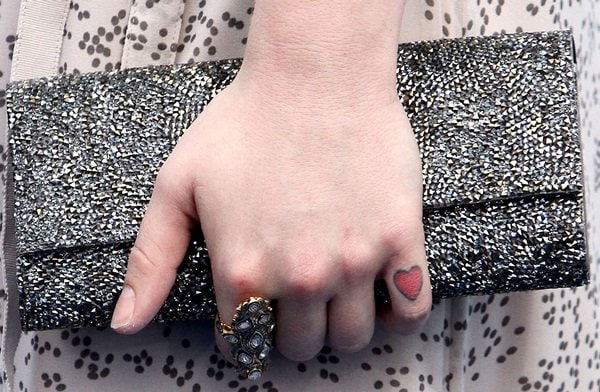 Kelly Osbourne shows off unpainted nails, Samira 13 jewelry and a heart-shaped tattoo on her pinky finger while holding a Judith Leiber clutch