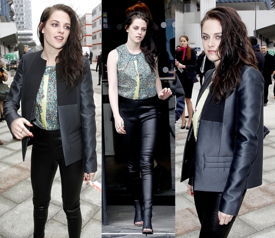 Kristen Stewart wore a floral sleeveless shell top under a collarless black satin blazer and skintight black leather pants that melded into her black open toe sandal booties