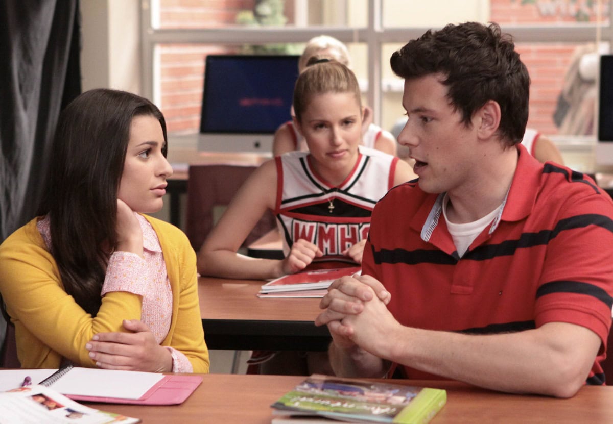 Lea Michele as Rachel Berry, Cory Monteith as Finn Hudson, and Dianna Agron as Quinn Fabray share a tense moment in the classroom on Glee, blending drama with preppy high school style
