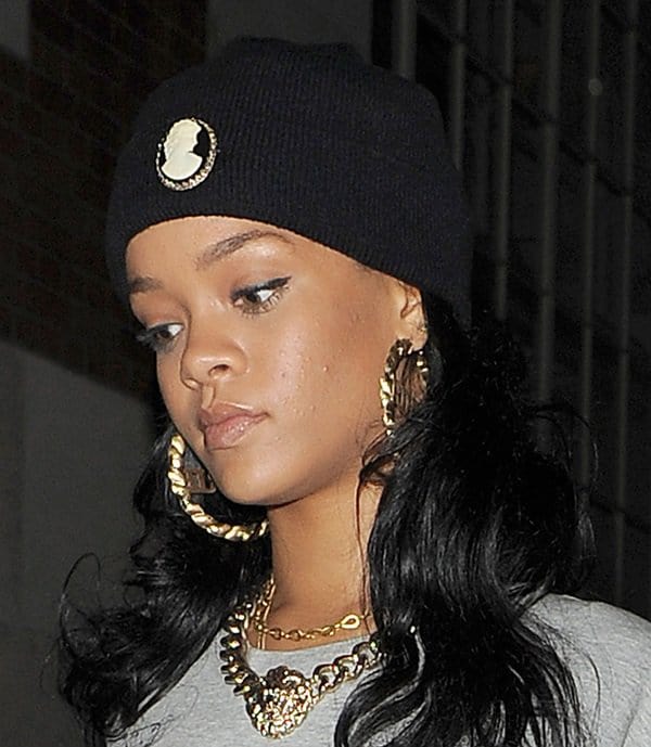 Rihanna complemented her outfit with striking accessories, notably wearing a Silver Spoon Attire vintage cameo beanie and a distinctive pair of earrings