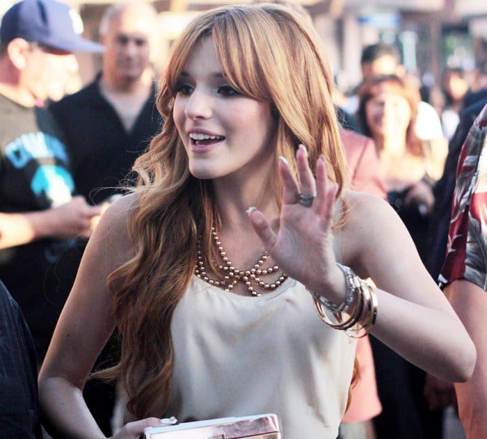 Bella Thorne wears a nude blouse with a statement necklace and bracelets