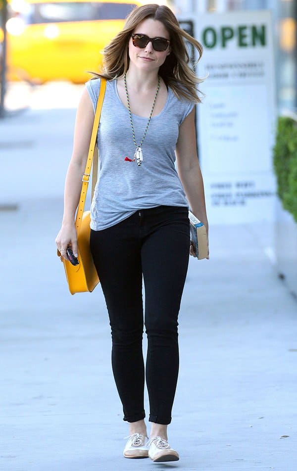 Sophia Bush adds a playful pop of color to her casual look with a bright yellow Cambridge Satchel Company bag, paired effortlessly with black skinny jeans and canvas sneakers