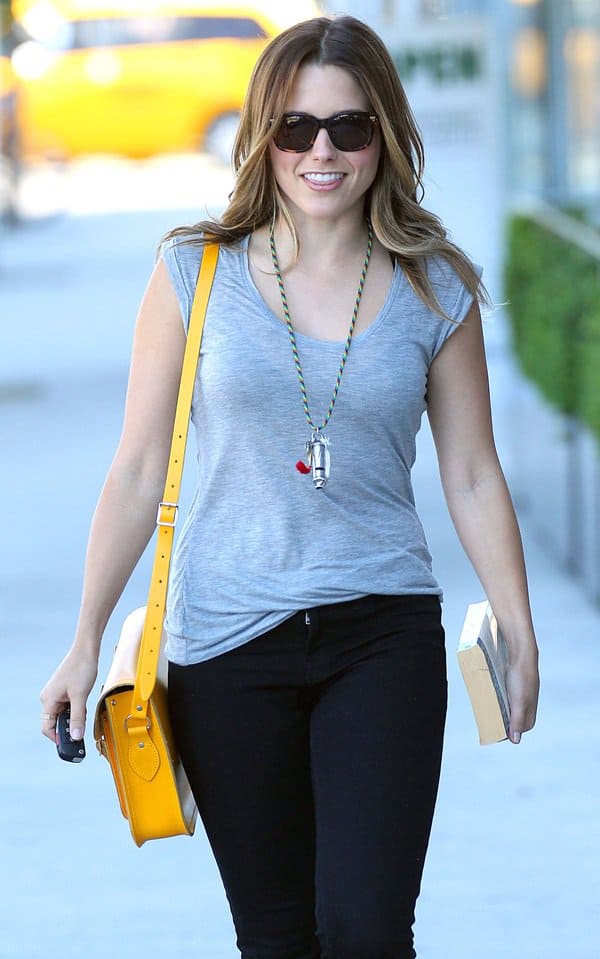 Sophia Bush keeps it casual-chic with a yellow Cambridge Satchel slung over her shoulder and a copy of The Portable Dorothy Parker in hand
