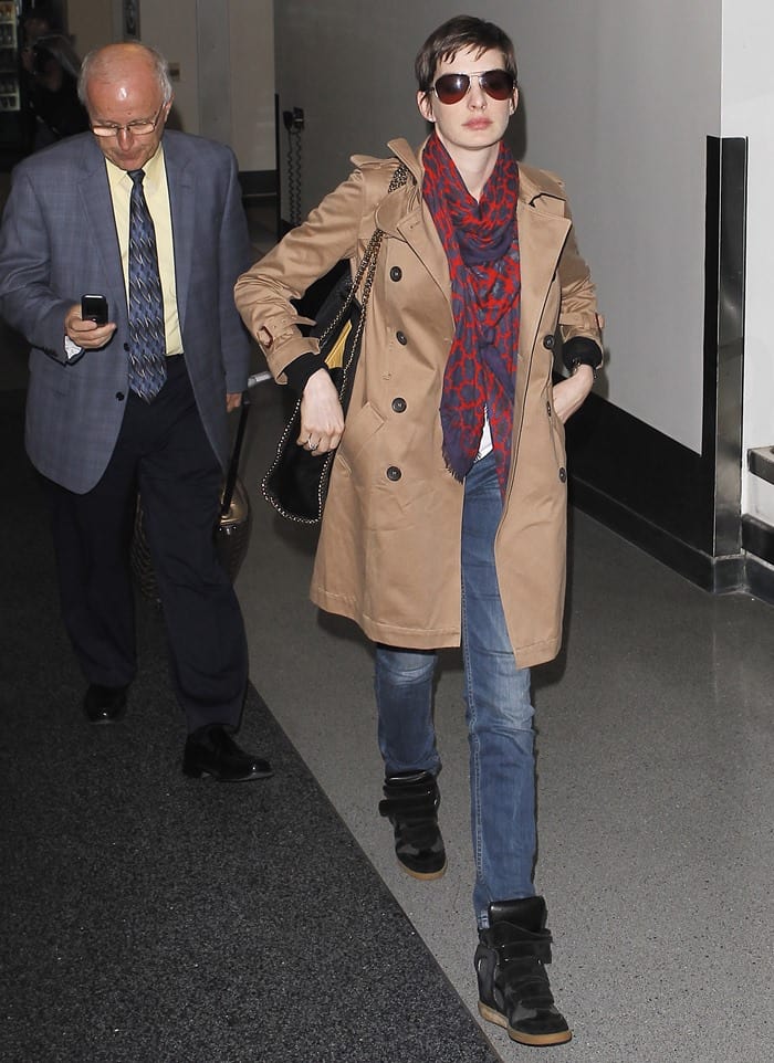 Anne Hathaway's androgynous, boy-meets-girl style, featuring a classic trench, snazzy scarf, jeans, sneaker wedges, pixie cut, and Ray-Bans, was intriguingly chic