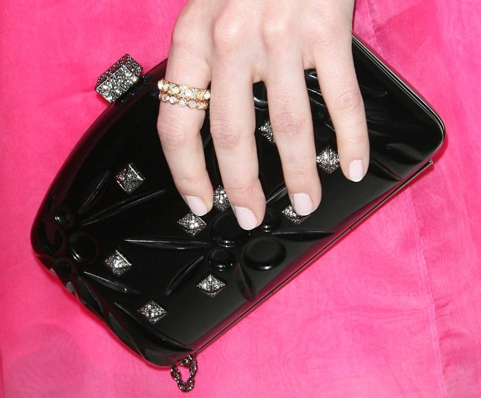 Emma Stone accessorizes with pastel pink nails, gold rings and an embellished black clutch