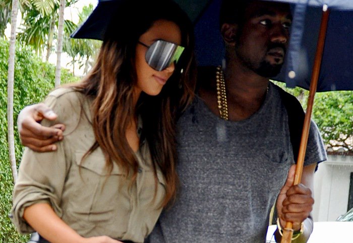 Kim Kardashian and Kanye West cuddled together under an umbrella