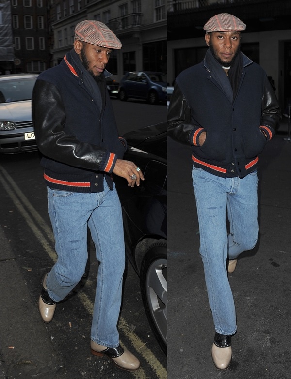 Mos Def in blue jeans styled with a brown newsboy cap and a black and navy blue varsity jacket