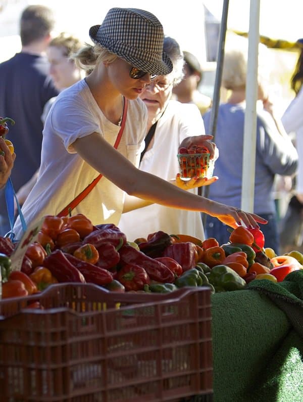 Accessorizing to perfection, Elizabeth Banks pairs her laid-back farmers market attire with a chic tweed trilby hat and stylish sunglasses, a true reflection of her polished yet approachable fashion sense