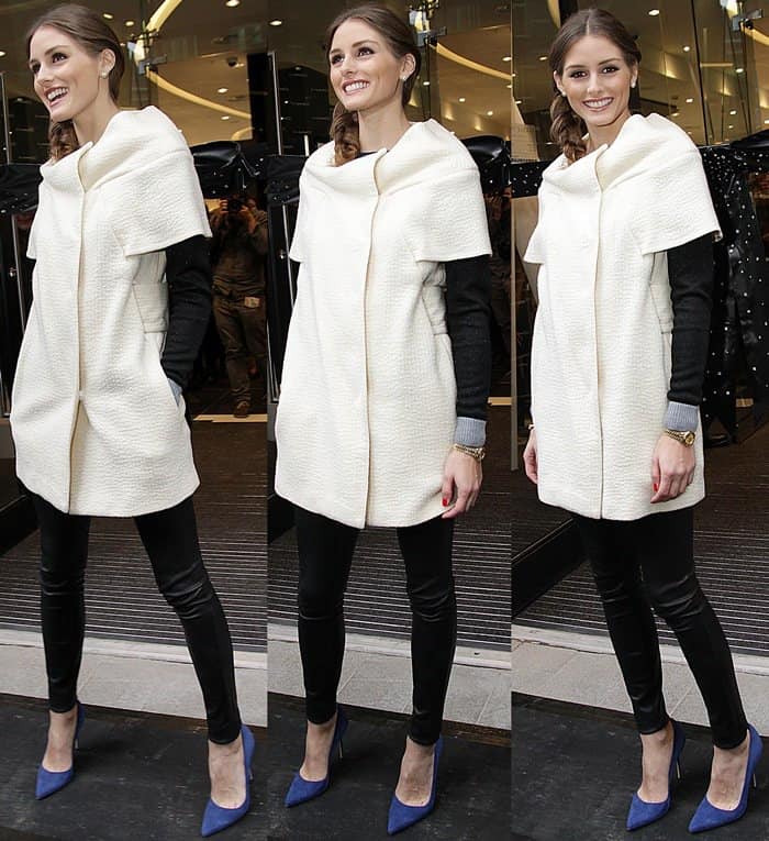 Olivia Palermo pairs a cream coat dress with black leather pants and bold blue pointy pumps, adding a vibrant pop of color to her sleek layered look