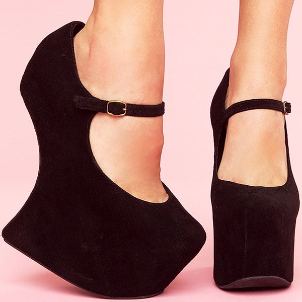 A dainty Mary-Jane strap details a dark suede pump set upon a stunning sculpted wedge heel