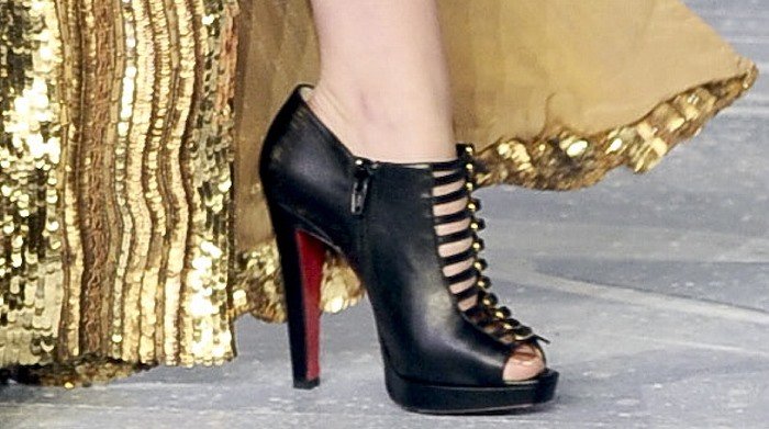 A close-up of Kristen Stewart's black Christian Louboutin "Manon" peep-toe booties featuring multiple straps and the signature red sole