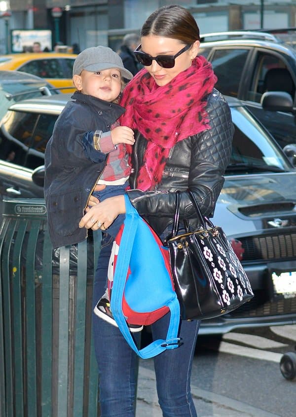 Supermodel grace, motherly embrace: Miranda Kerr is spotted in New York City exuding elegance and poise, balancing her son Flynn and a statement Prada floral applique 'Spazzolato' bag