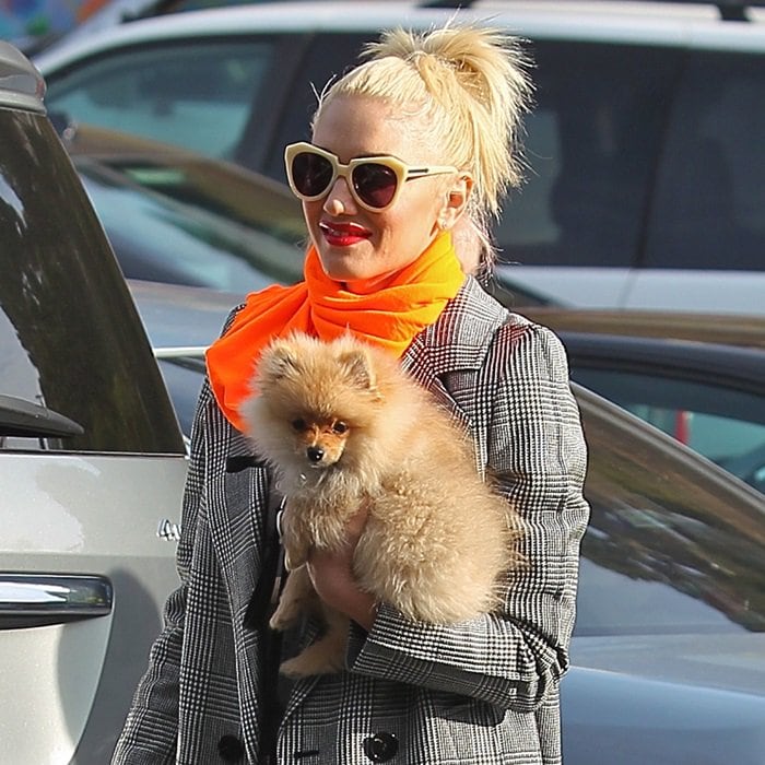 Gwen Stefani turns heads with her striking neon orange scarf, a bold accent to her ensemble