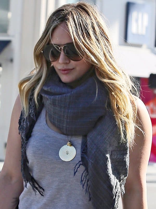 Elevating a simple ensemble with a touch of glamour, Hilary Duff pairs her Gucci sunglasses with a sophisticated fringed scarf, showcasing her flair for accessorizing and making a casual outfit stand out