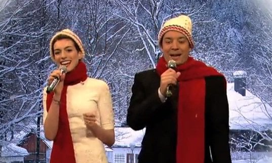 Anne Hathaway wears a red scarf while singing with Jimmy Fallon on Late Night With Jimmy Fallon
