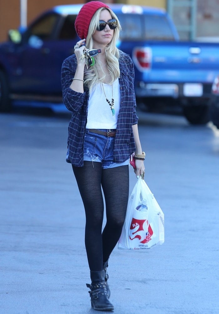 Ashley Tisdale added her studded cowboy-inspired biker booties to tights, jean shorts, a plaid shirt, and a red beanie