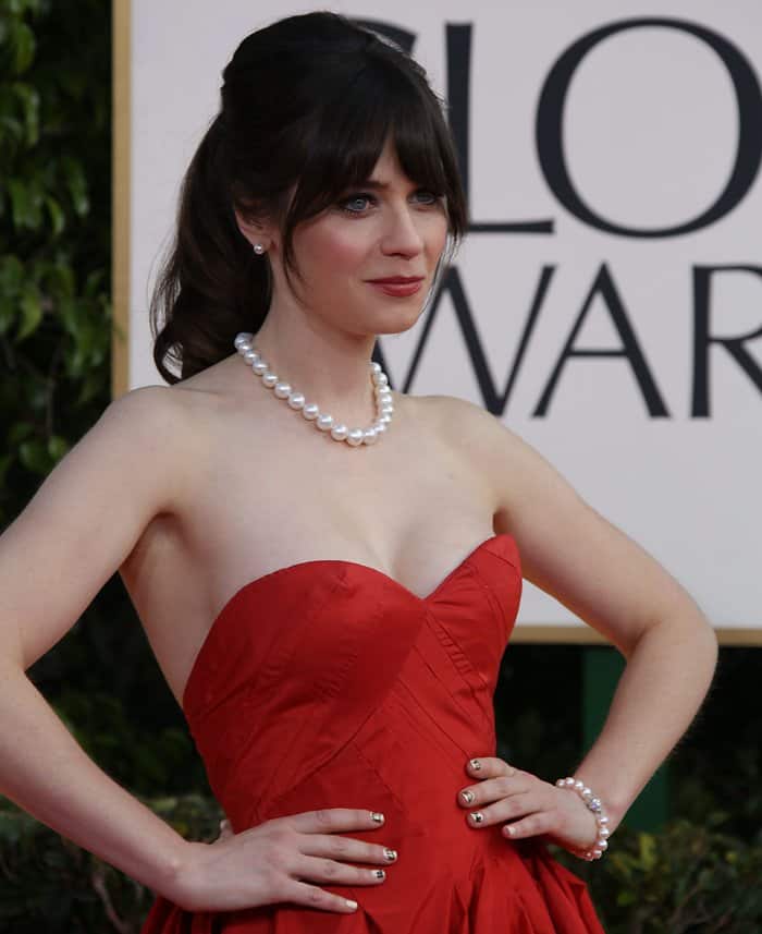 Zooey Deschanel exudes classic Hollywood glamour in a striking red gown paired with elegant pearls, attending the Golden Globe Awards