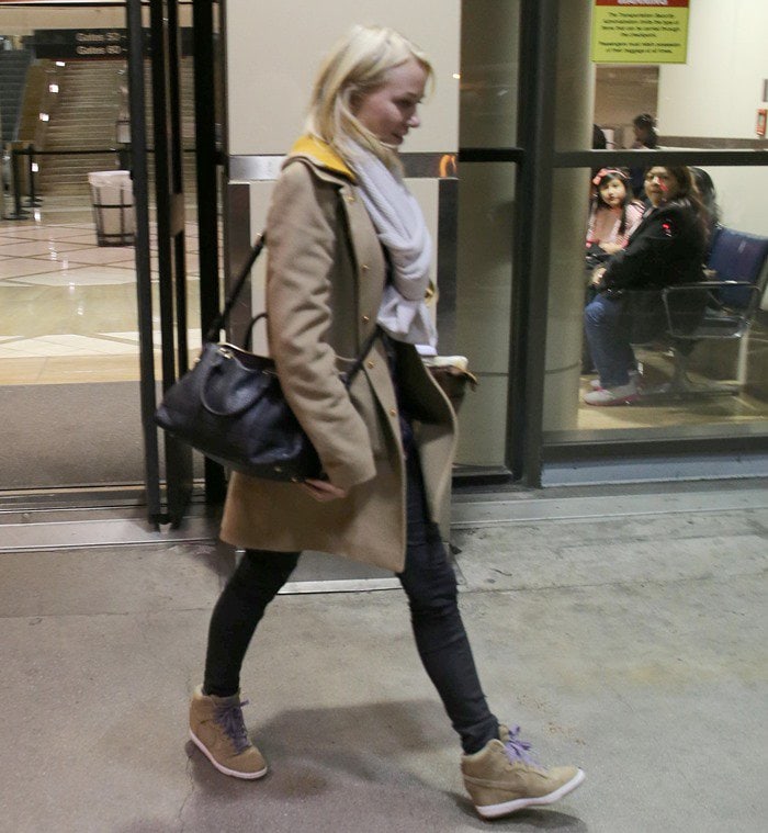 Naomie Watts matches her tan Nike wedge sneakers to a tan single-breasted coat 