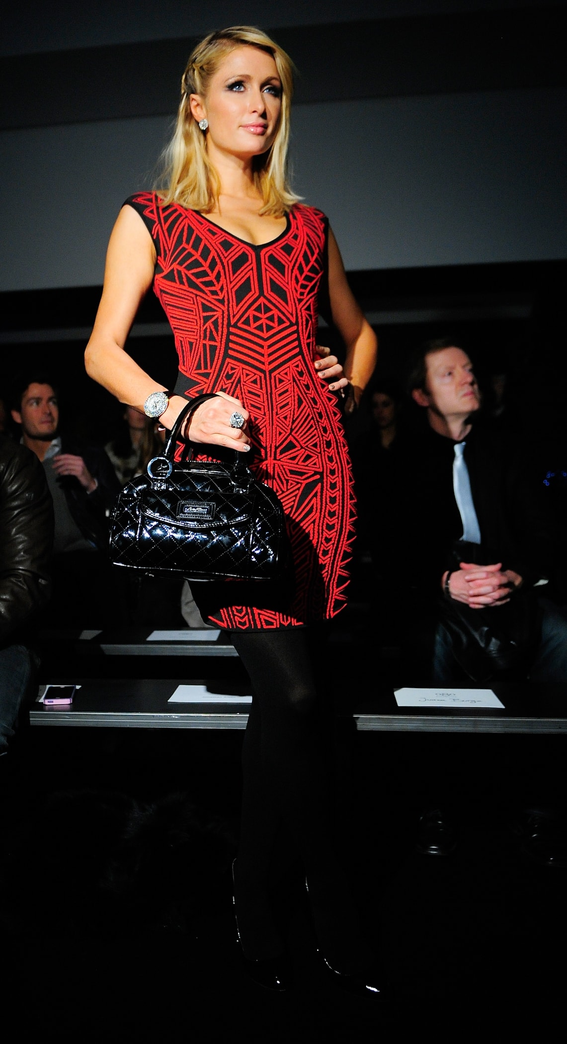 At the Mango Fashion Show in Barcelona on January 28, 2013, Paris Hilton elegantly sported an Rvn abstract jacquard mini dress paired with Prada black patent leather silver heels