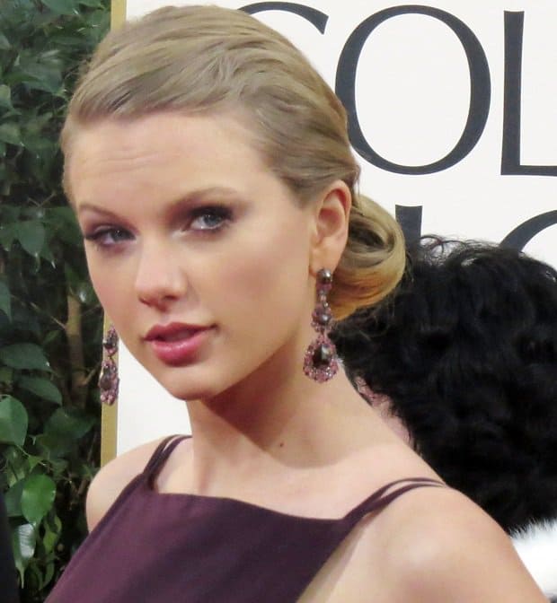 Taylor's sleek Grace Kelly-inspired updo and teardrop earrings add elegance to her bold, body-contouring taffeta gown