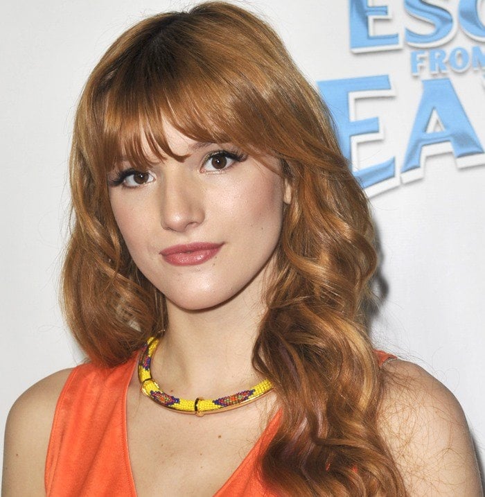 Bella Thorne brings vibrant color to the Escape from Planet Earth premiere, wearing a bright orange BCBGMAXAZRIA dress and a playful beaded necklace