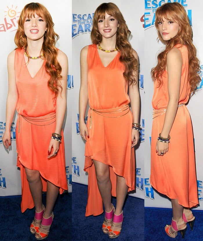 Bella Thorne wears a bright orange BCBGMAXAZRIA dress on the blue carpet