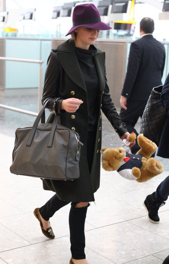 Carrying a cute stuffed teddy bear, Jennifer Lawrence wears a Burberry London leather sleeve coat at LAX airport