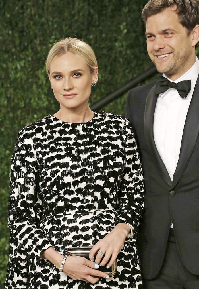 Diane Kruger stuns with a sleek center-parted updo, statement earrings, a bold monochrome abstract-patterned Giambattista Valli dress, and a metallic box clutch, showcasing elegant yet modern accessories