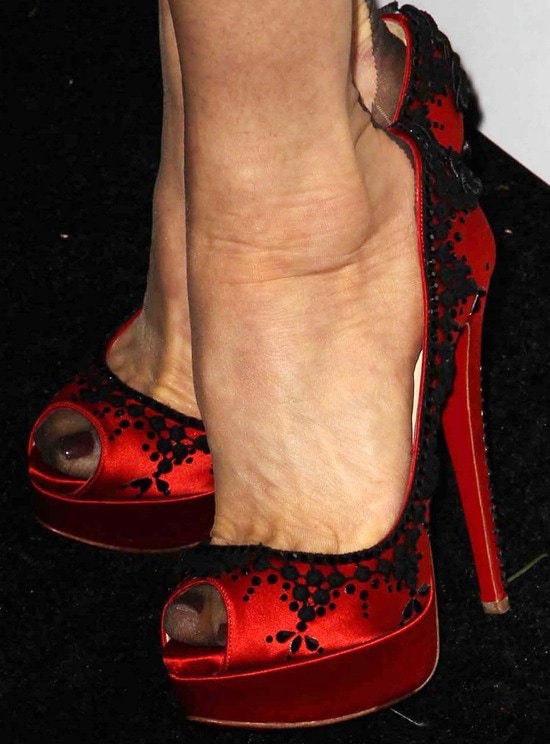 A close-up of Dita Von Teese's striking Christian Louboutin ‘Torero’ pumps showcasing intricate black lace details against bold red satin