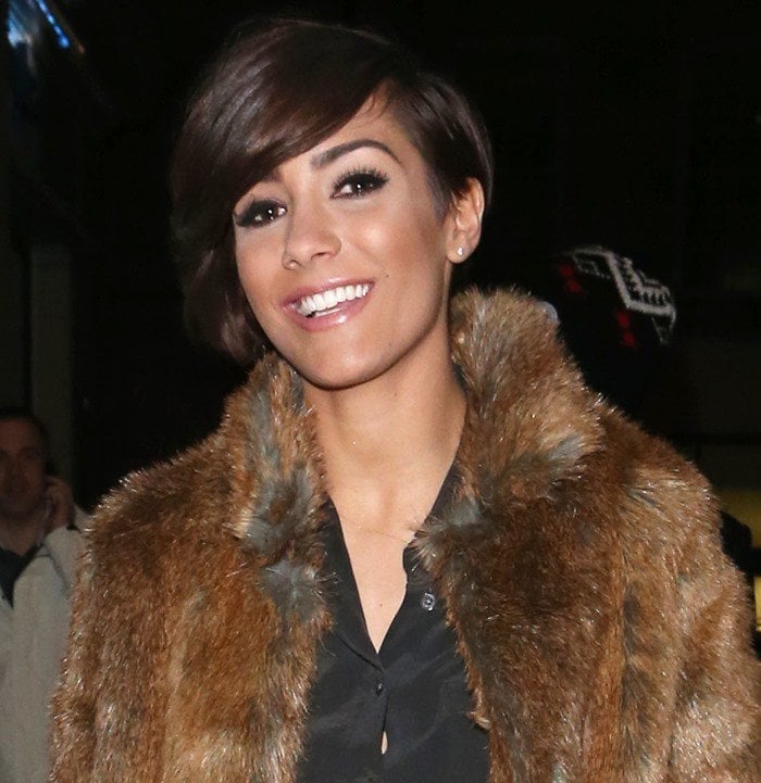 Frankie Sandford side parts her cropped brunette hair as she leaves the May Fair Hotel