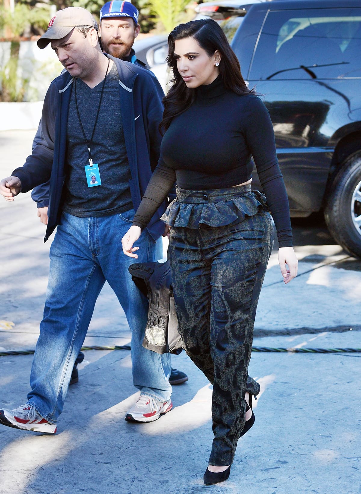 Kim Kardashian embraced her pregnancy with bold style, stepping out from her Beverly Hills home in snug, metallic sheen animal-print pants with a peplum ruffle, a tight cropped turtleneck, big diamond earrings, and black stiletto heels, highlighting her curvy figure