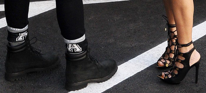 A striking contrast in footwear: rugged black combat boots meet Kourtney Kardashian’s glamorous Tom Ford lace-up heels with gold accents