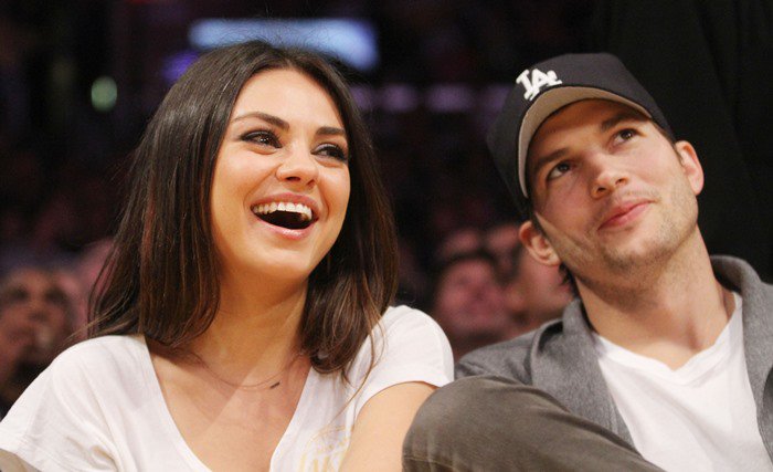 Mila Kunis laughs as she attends a Lakers game with partner Ashton Kutcher