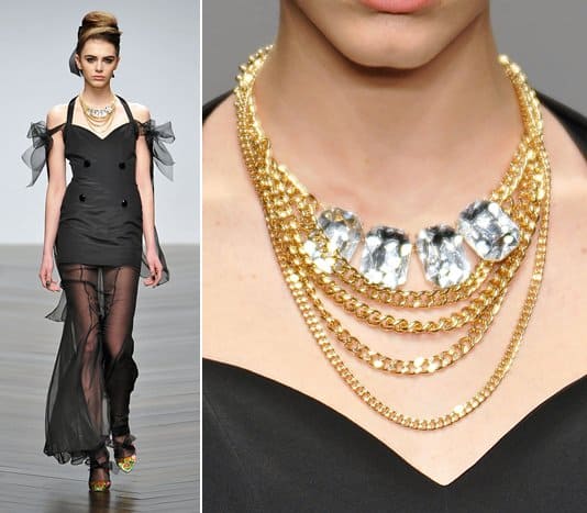 A model wears a faceted crystal necklace with layered gold chains