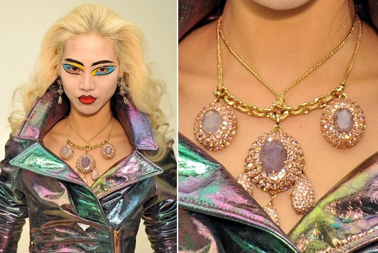 A model wears a gold crystal-encrusted cabochon pendant necklace