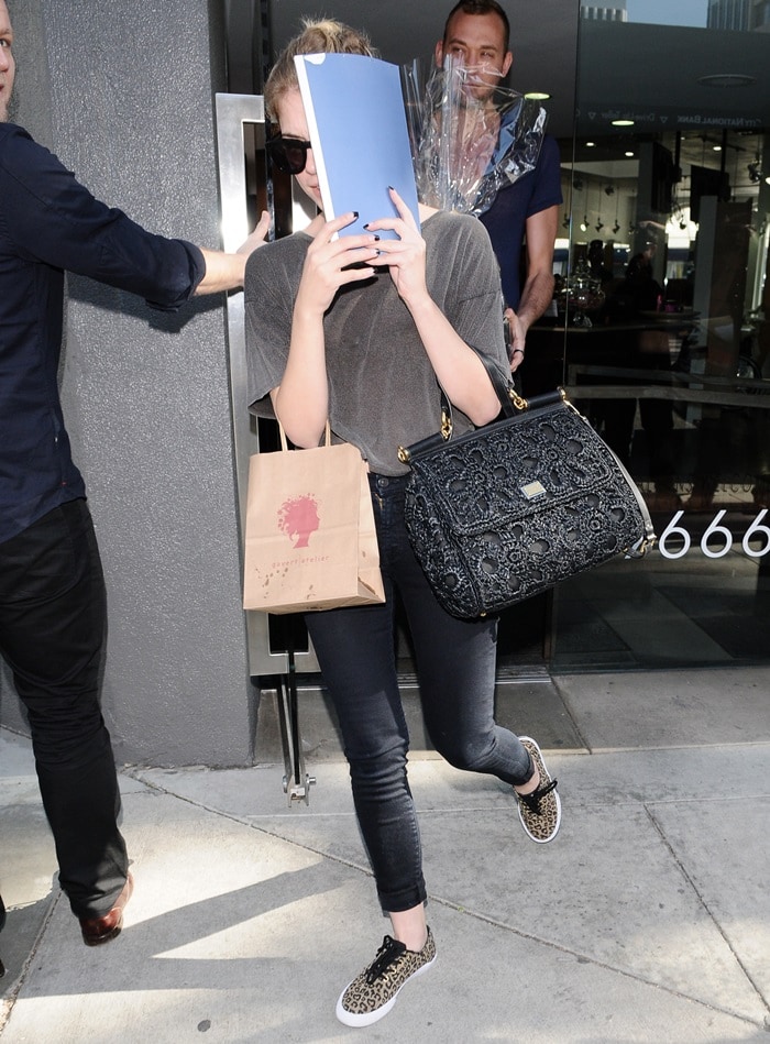 Ashley Benson wearing a casual chic ensemble that featured Dolce & Gabbana's Miss Sicily Raffia Satchel, 7 For All Mankind skinny jeans, and Vans Authentic sneakers in leopard print