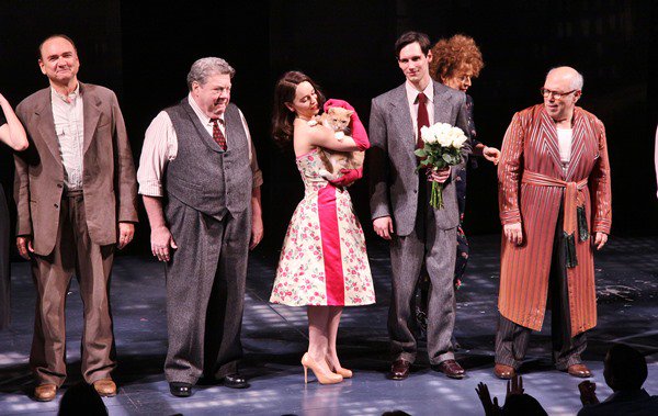 Emilia Clarke in a striking floral dress by Colleen Atwood at the opening night's curtain call, showcasing a vibrant departure from the expected black dress