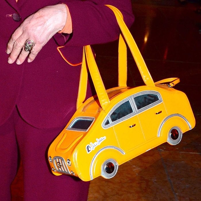 Heidi Hetzer carries a playful yellow car purse, blending her passion for racing with fashion