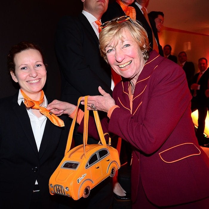 Heidi Hetzer showcases her unique car purse at a formal event in Berlin, highlighting her distinctive style