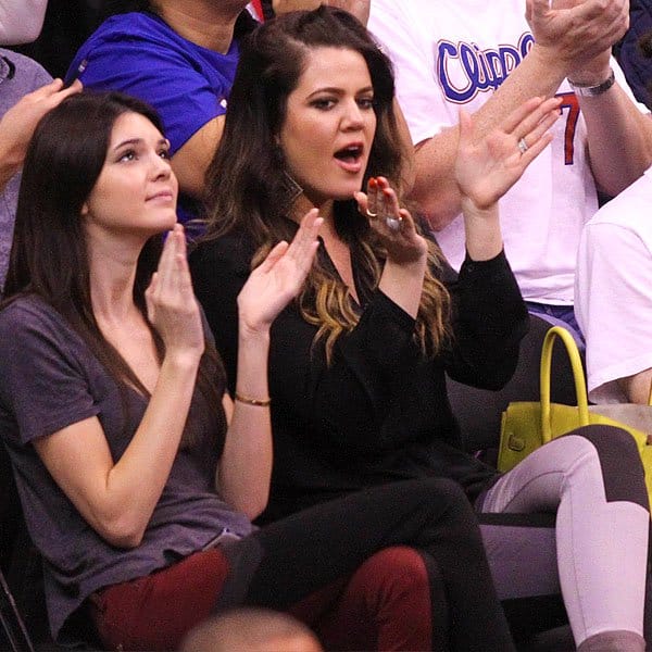 A spirited display of support: Kendall Jenner and Khloe Kardashian cheer on the LA Clippers, coordinated in striking paneled jeans, showcasing their unique style and unity at the basketball game
