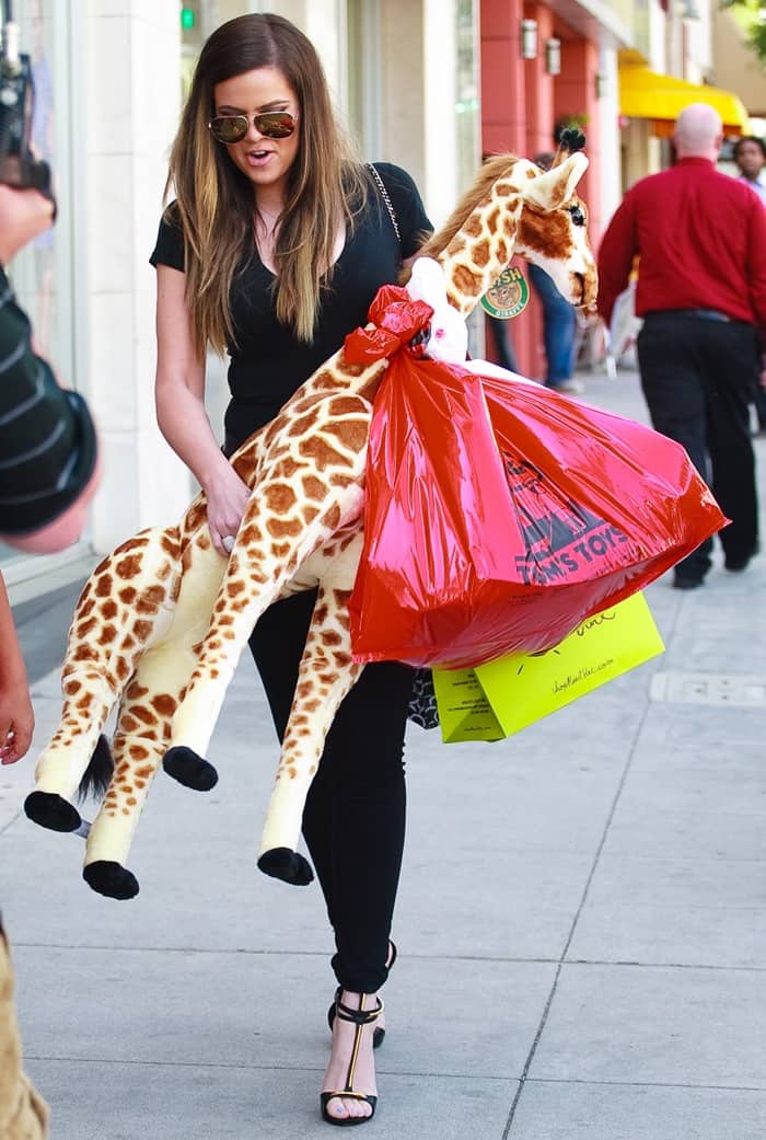 Khloe Kardashian in an all-black ensemble consisting of tight black trousers and a tight v-neck t-shirt